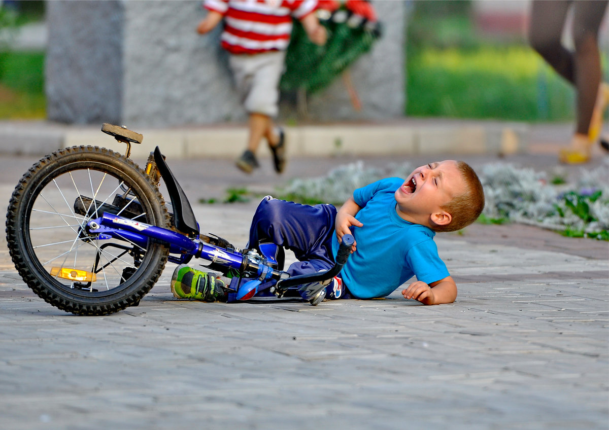 Мальчик падает с велосипеда